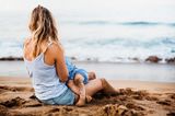 Mutter stillt ihr Kind am Strand