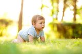 Baby krabbelt im Body durch Gras