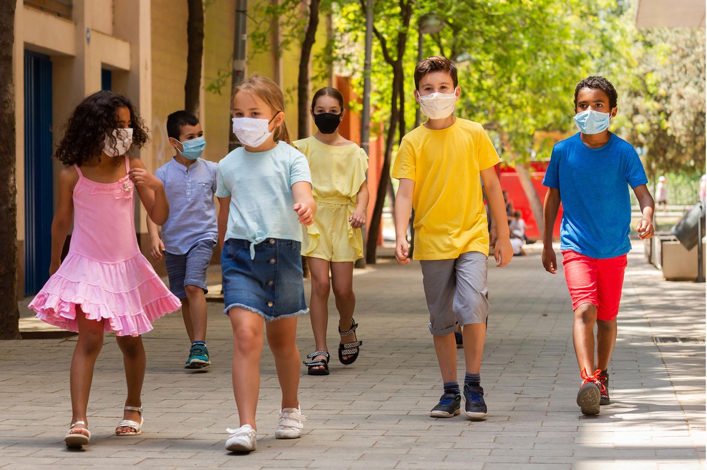Kinder mit Masken verlassen die Schule