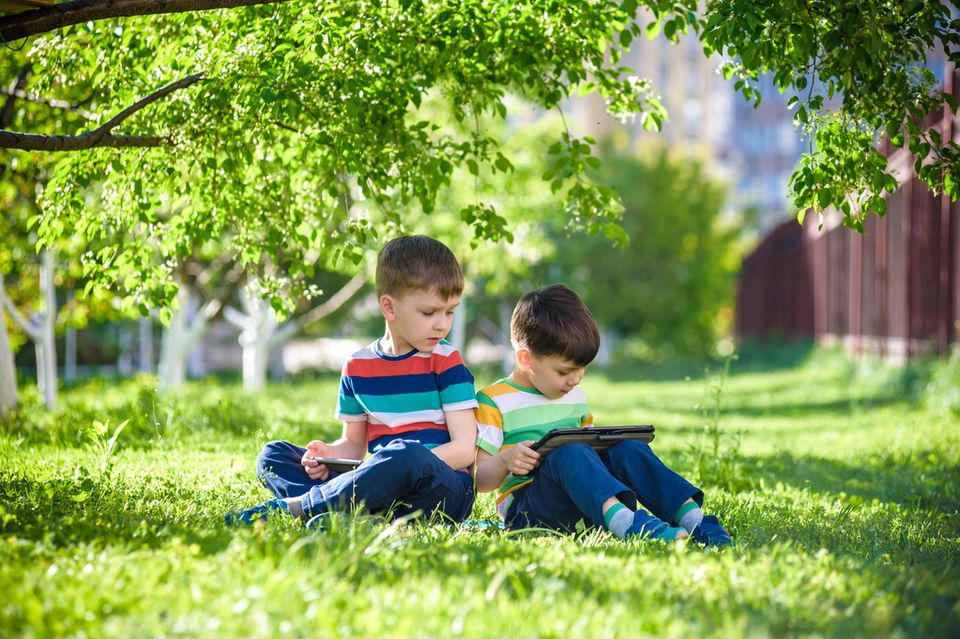 Zwei Jungen lernen draußen mit einem Tablet