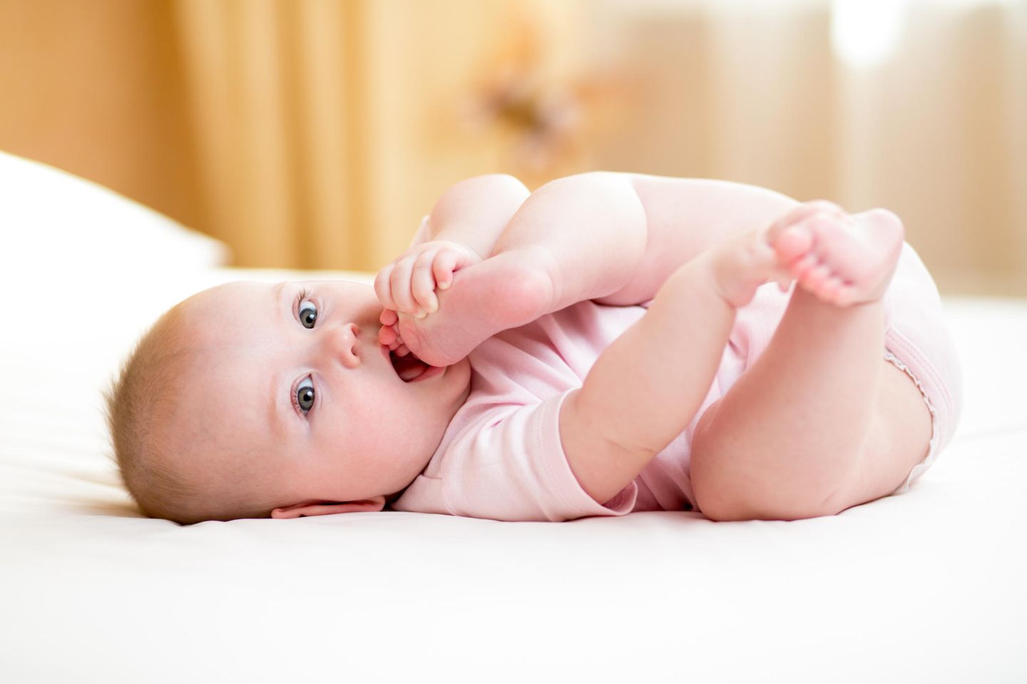 Alltagsgegenstände: Baby beißt sich in den Fuß