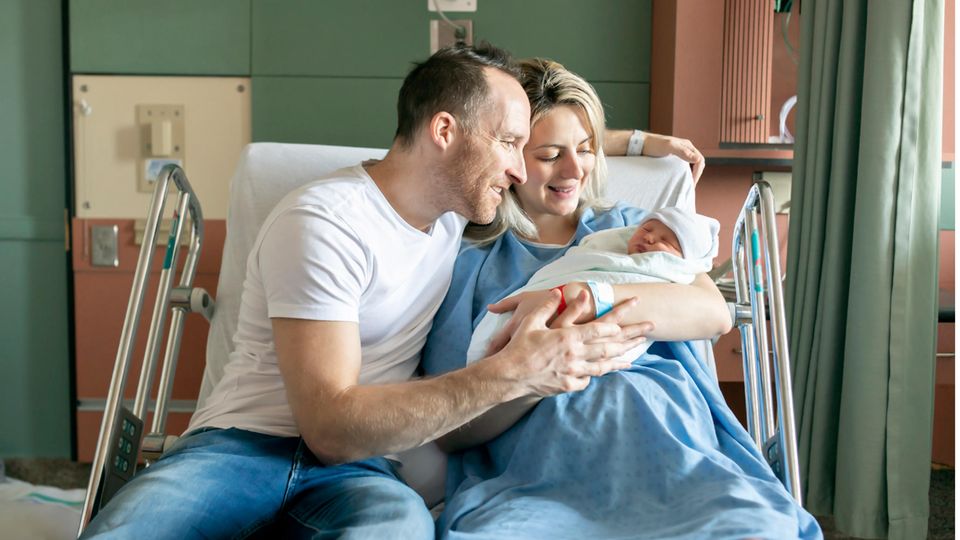 Glückliche Eltern halten ihr Neugeborenes in den Armen