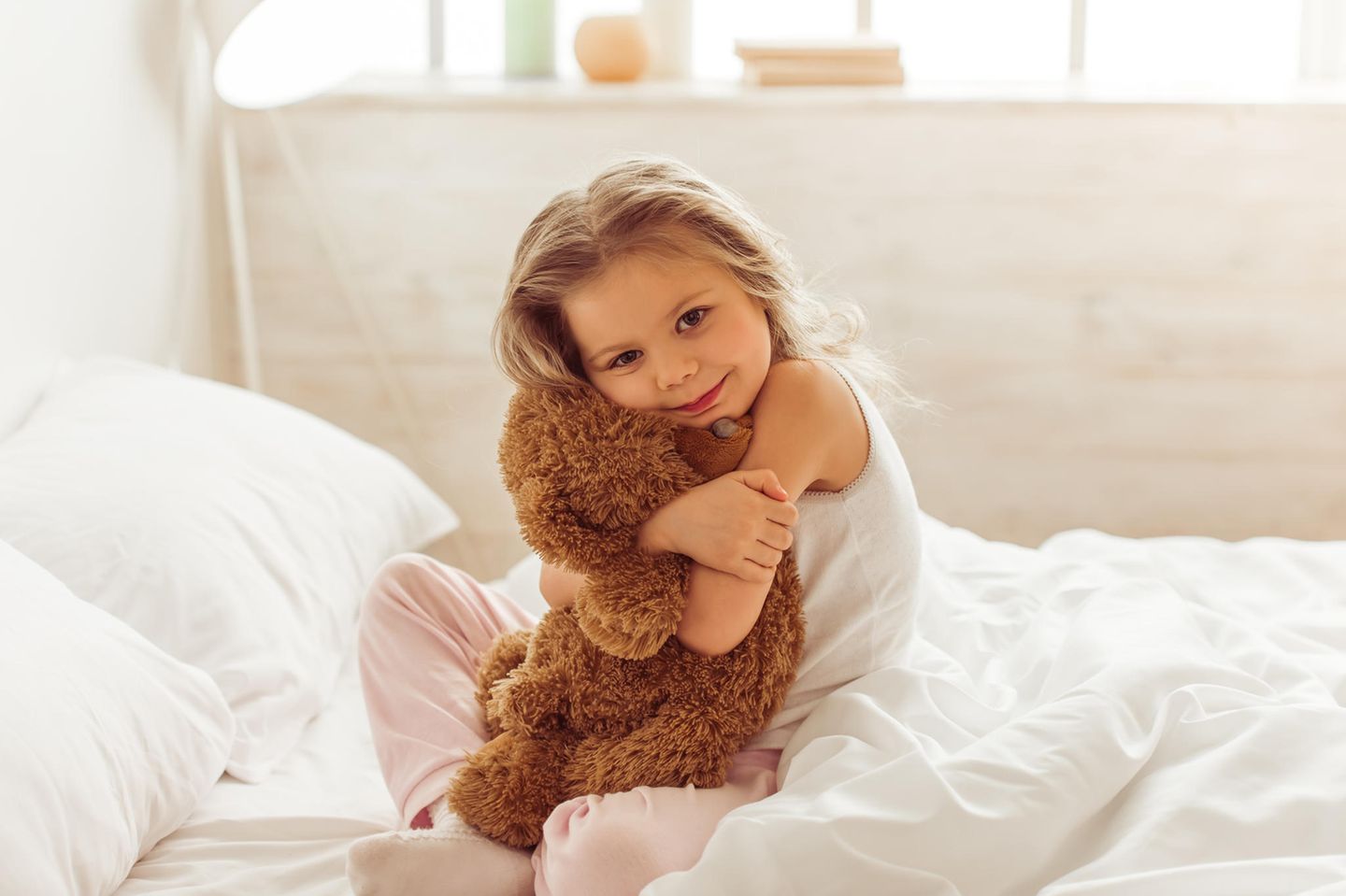 Mädchen mit Teddy im Bett