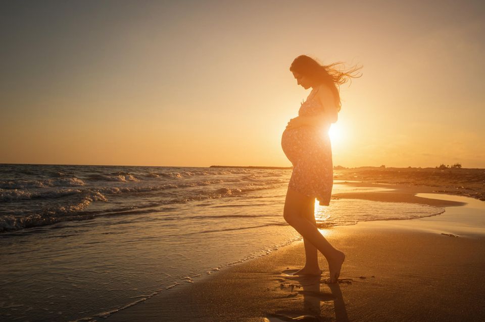 Schwangere bei Sonnenuntergang am Strand