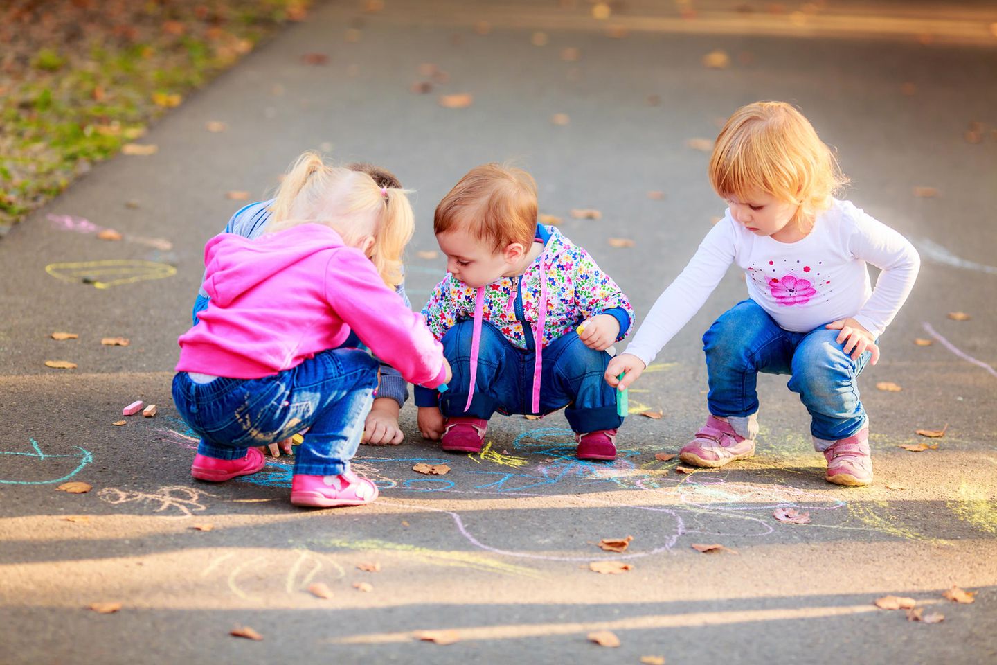 Drei Kinder malen auf Einfahrt mit Kreide