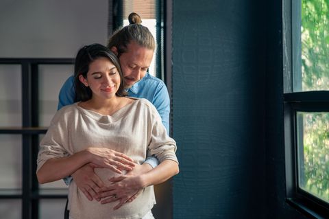Mann hält den Bauch einer schwangeren Frau