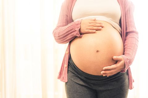 Hochschwangere Frau hält ihren Bauch