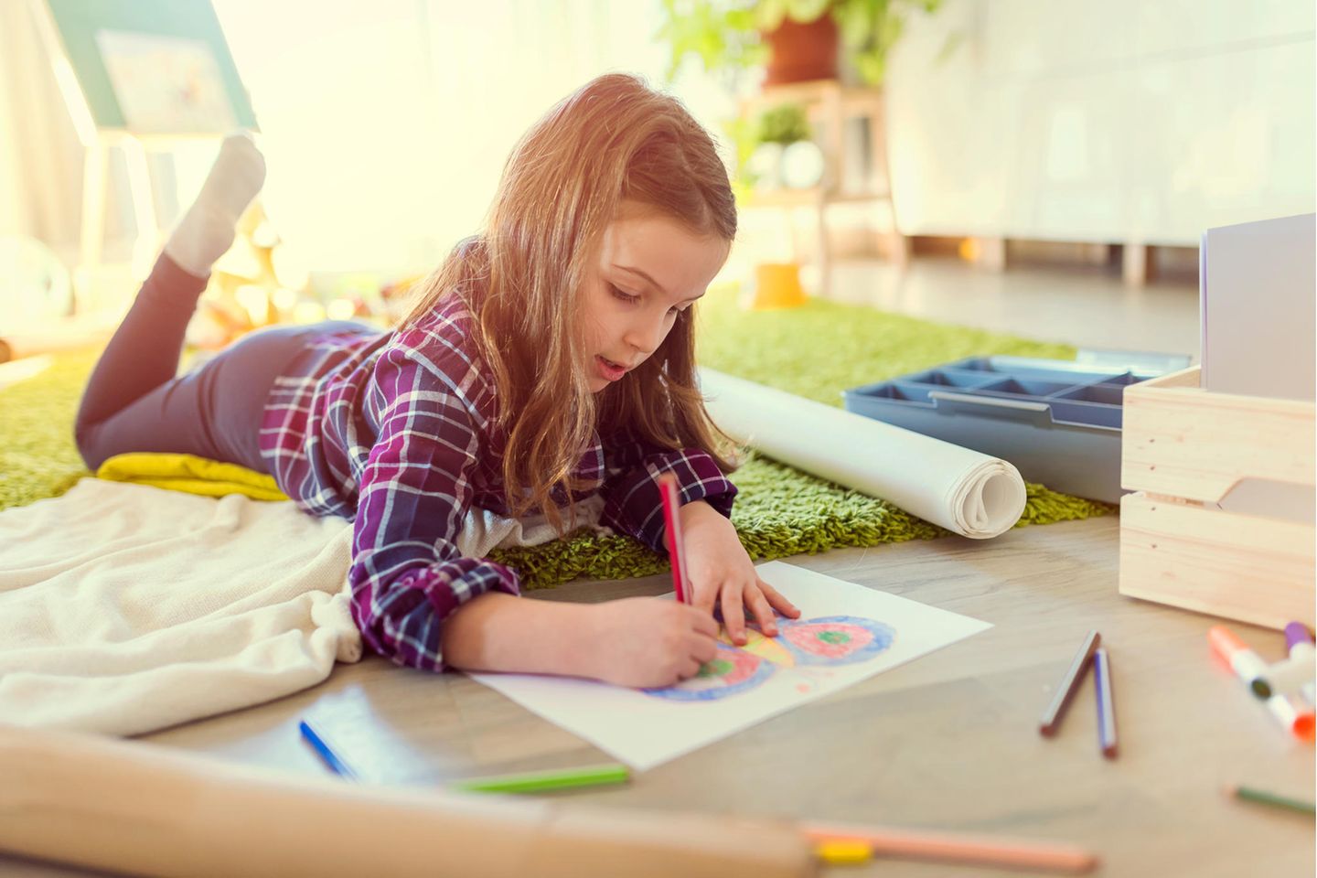 Junges Mädchen malt in Heft auf dem Boden