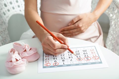 Eine schwangere Frau macht mit einem Filzstift eine Strichliste auf ihren Babybauch.