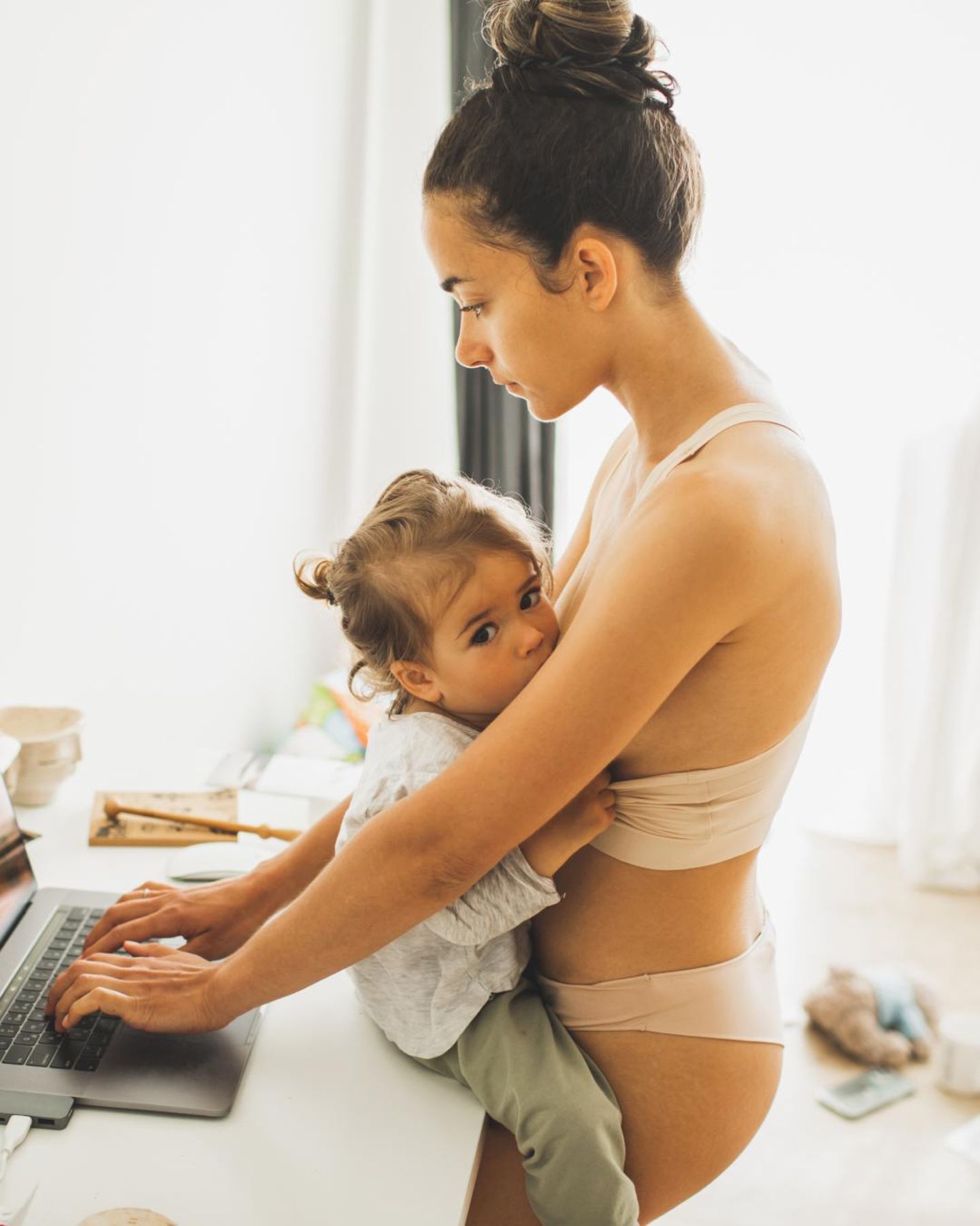 Postpartum Unfiltered: Frau mit Kind am Laptop