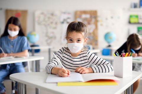 Ein junges Mädchen trägt in der Schule eine Maske.