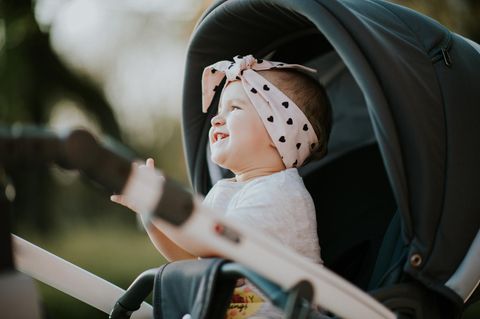 Buggy-Test: Grinsendes Kleinkind sitzt draußen im Buggy