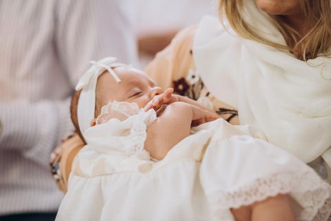 Baby in weißem Kleid bei Taufe