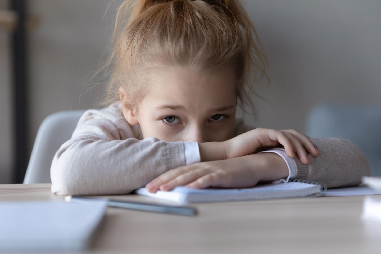 Frustriertes Mädchen stützt sich auf ihren Schulsachen ab