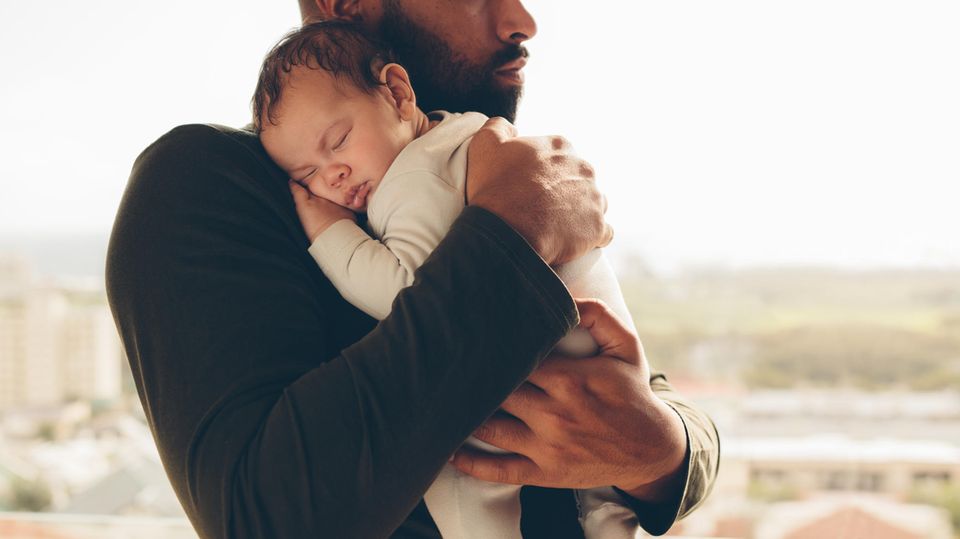 Ein frischgebackener Vater hält sein Neugeborenes auf dem Arm .