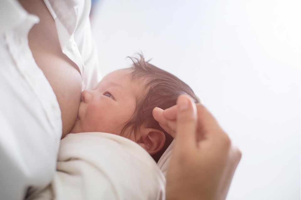 Stillende Mutter mit Neugeborenem im Arm