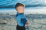 Kleiner Junge am Strand mit an der Kopfseite einrasiertem Spinnennetz
