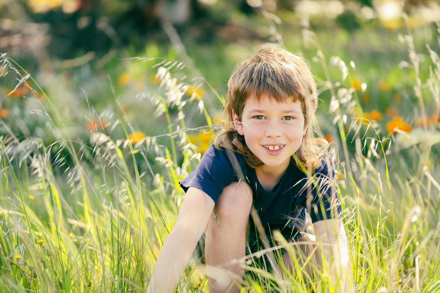 Junge mit Vokuhila Haarschnitt auf einer Blumenwiese