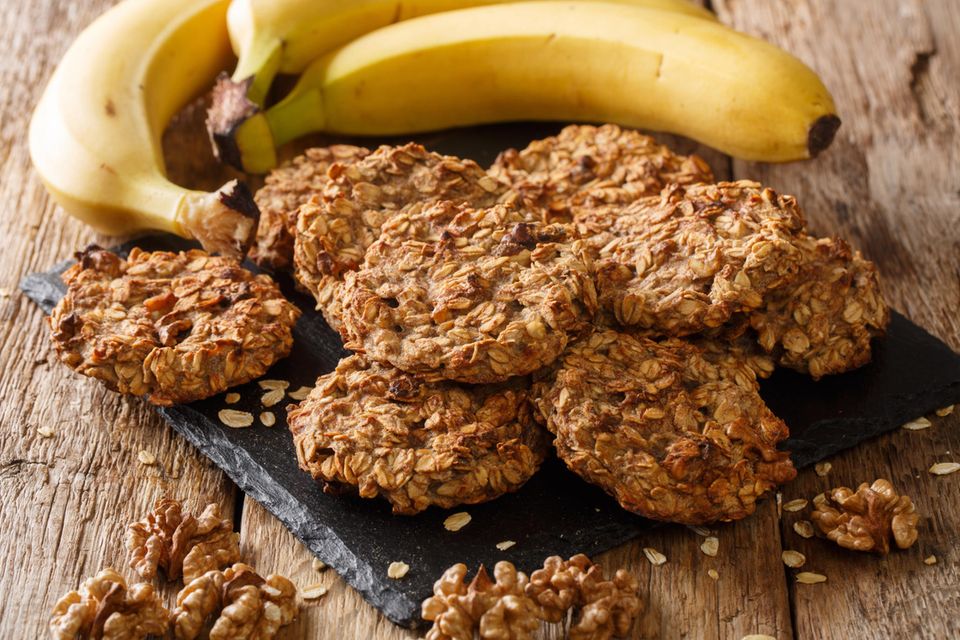 Blitz-Plätzchen: Auf einer schwarzen Platte liegen Haferkekse, daneben liegen Bananen.
