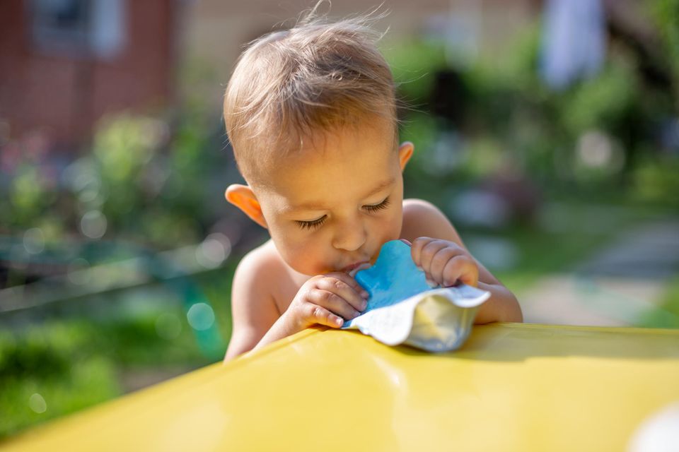 Quetschies selbst machen: Ein kleiner Junge trinkt aus einem hellblauen Quetschbeutel