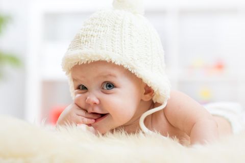 Ein Baby lacht verschmitzt in die Kamera