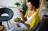 Lächelnde Frau isst bunten Salat