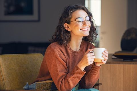 Lächelnde Frau mit Brille und Tasse in den Händen
