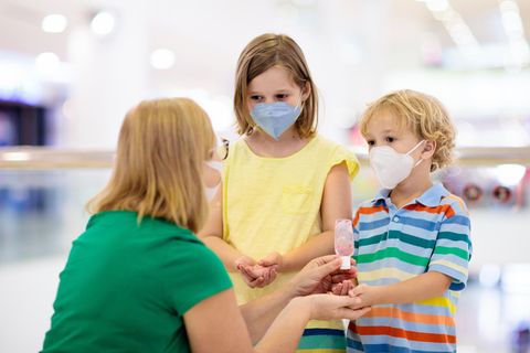 Mundschutz für Kinder: Mädchen und Junge mit FFP2-Masken bekommen die Hände desinfiziert.