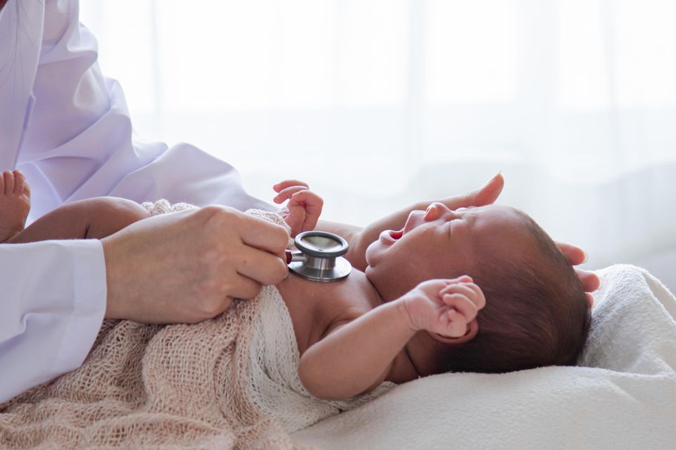 Ein Kinderarzt untersucht ein Neugeborenes.