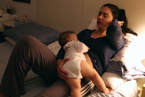 Mutter stillt ihr Baby in der Nacht auf ihrem Bett