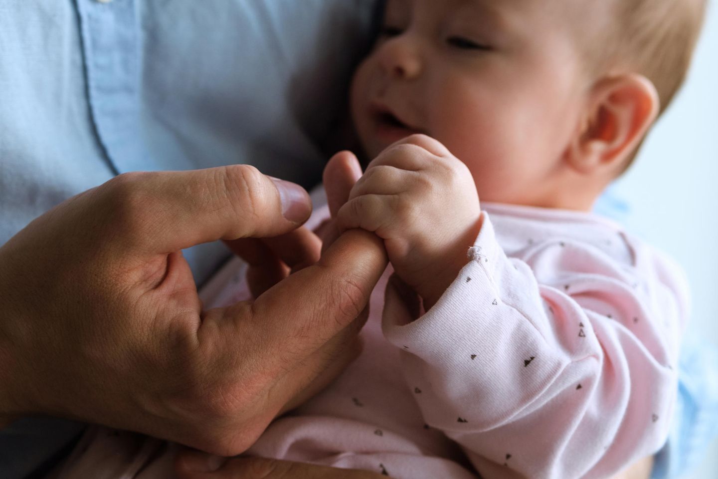 Verschnupftes Baby hält den Finger seines Papas