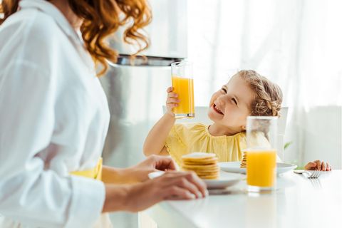 Ein kleines Mädchen genießt ein Glas Orangensaft