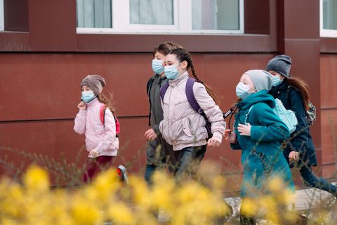 Kinder gehen mit medizinischen Masken zur Schule