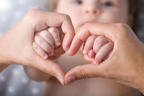 Sprüche zur Geburt: Eine Mutter bildet mit ihren Händen ein Herz vor dem Gesicht ihres Babys