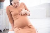 Negative Seiten in der Schwangerschaft: Schwangere Frau hält sich den Magen