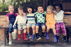 Lustige Kindersprüche: Kindergartenkinder sitzen auf einer Bank