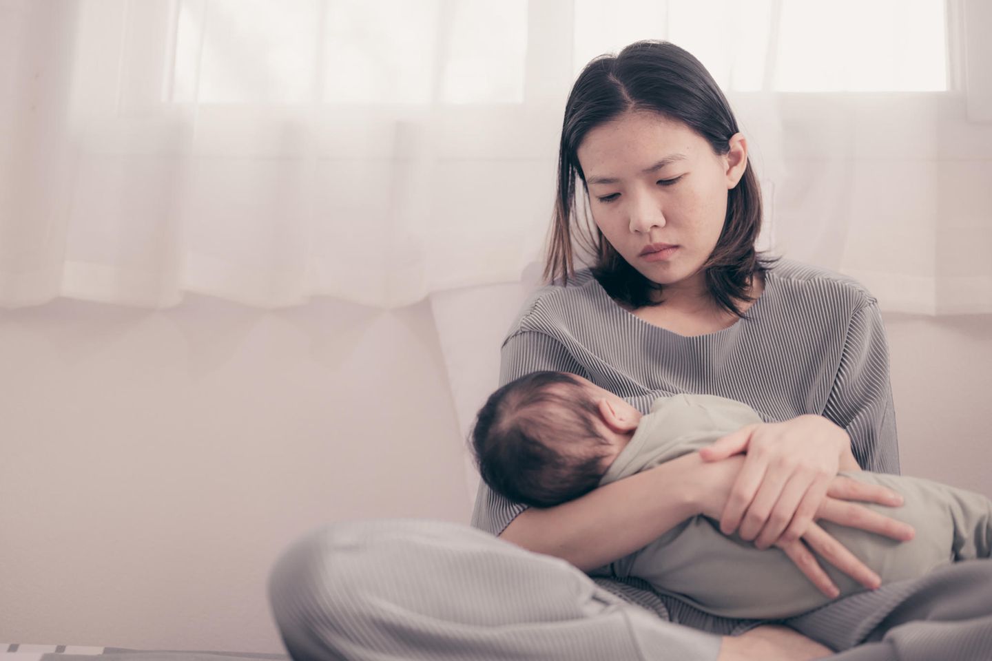 Wochenbettdepression: Mutter guckt ihr Baby traurig an