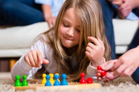 Spiele für Kinder: Mädchen vor Brettspiel mit bunten Spielfiguren.