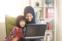 Team Rabeneltern: Mutter schaut mit Kind auf Laptop