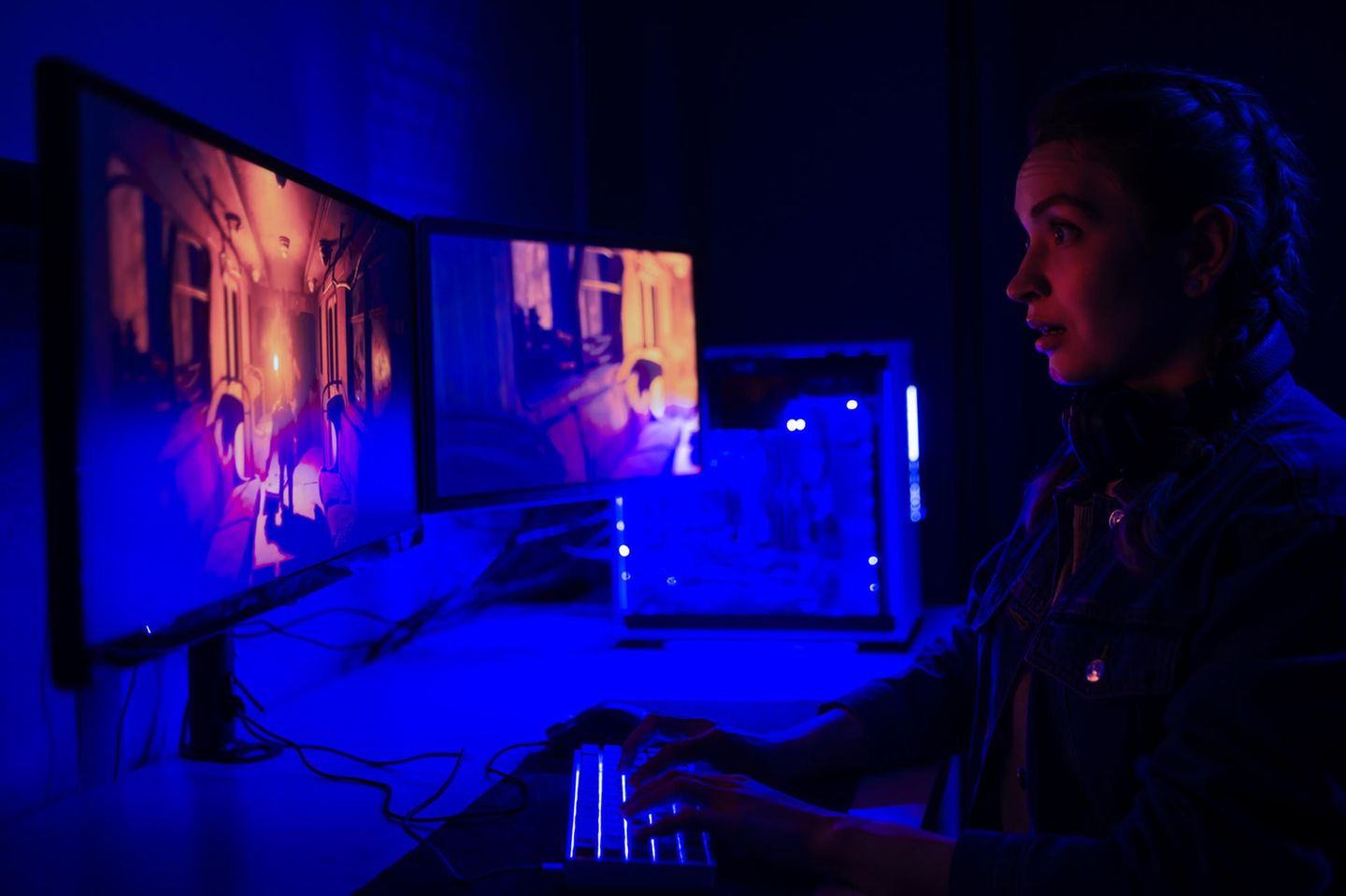 Junge Frau spielt im abgedunkelten Raum Videospiele