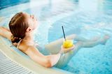 Junge Frau entspannt mit Drink im Pool