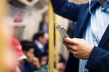 Mann mit Jackett hält Smartphone in der Bahn