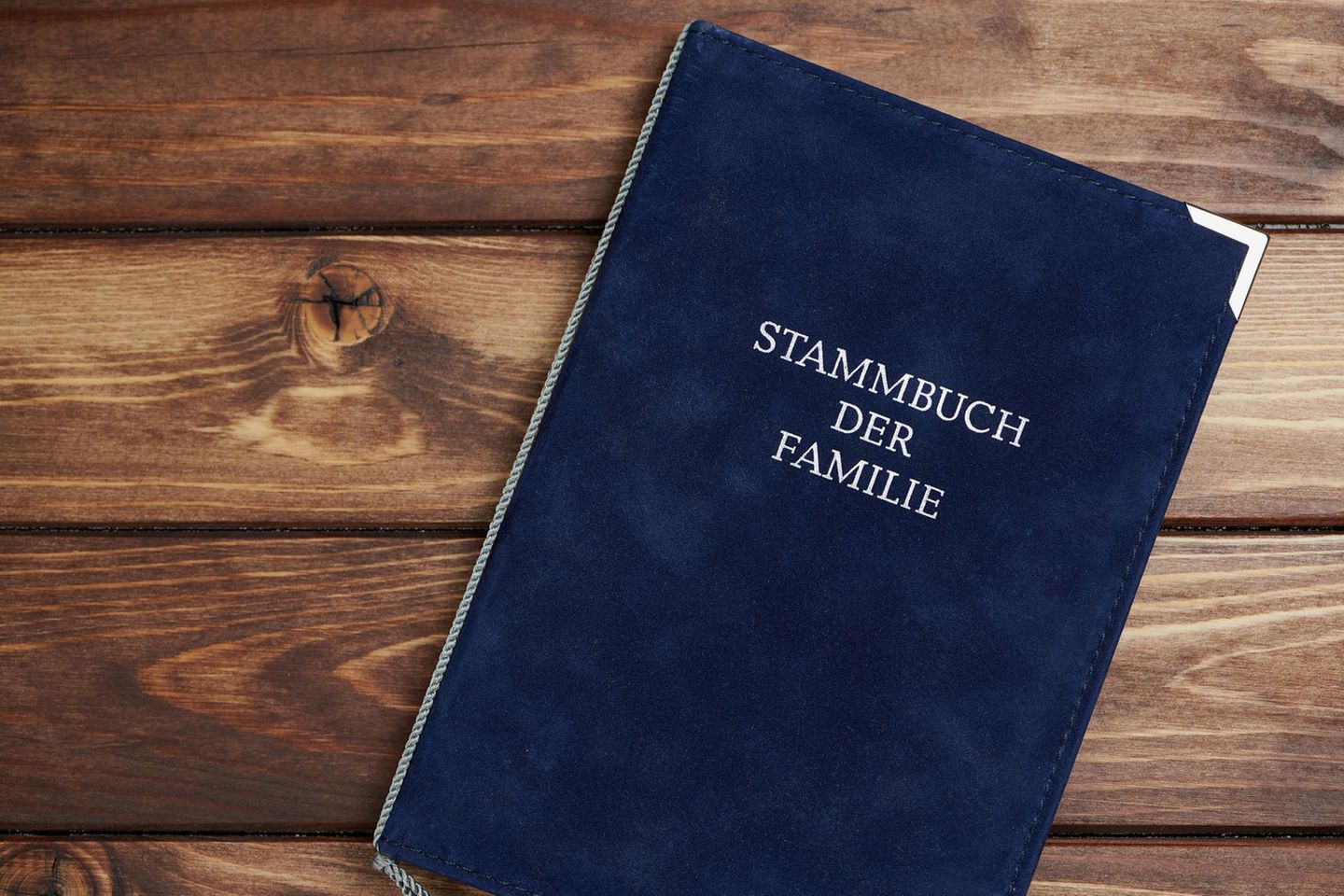 Ein blaues Familienstammbuch liegt auf einer Holzoberfläche