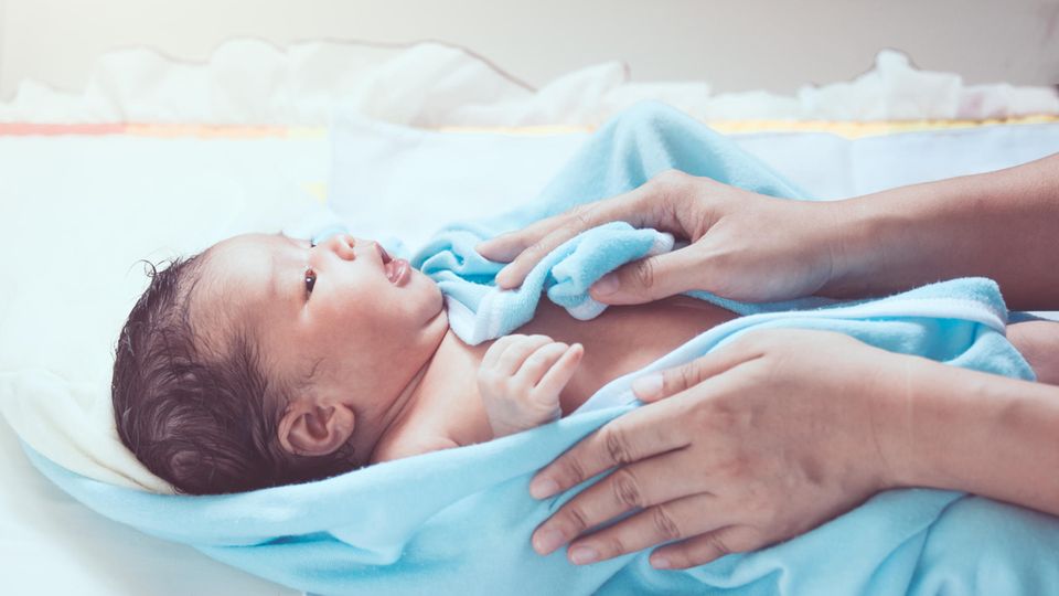 Ein Neugeborenes wird nach dem Waschen getrocknet.