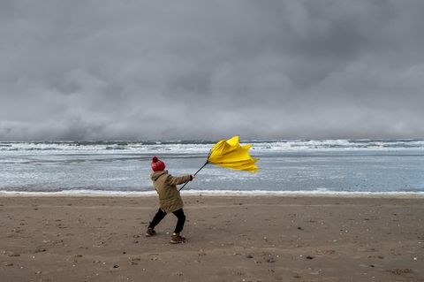 sturm-junge-am-stürmischen-meer-mit-kaputtem-regenschirm
