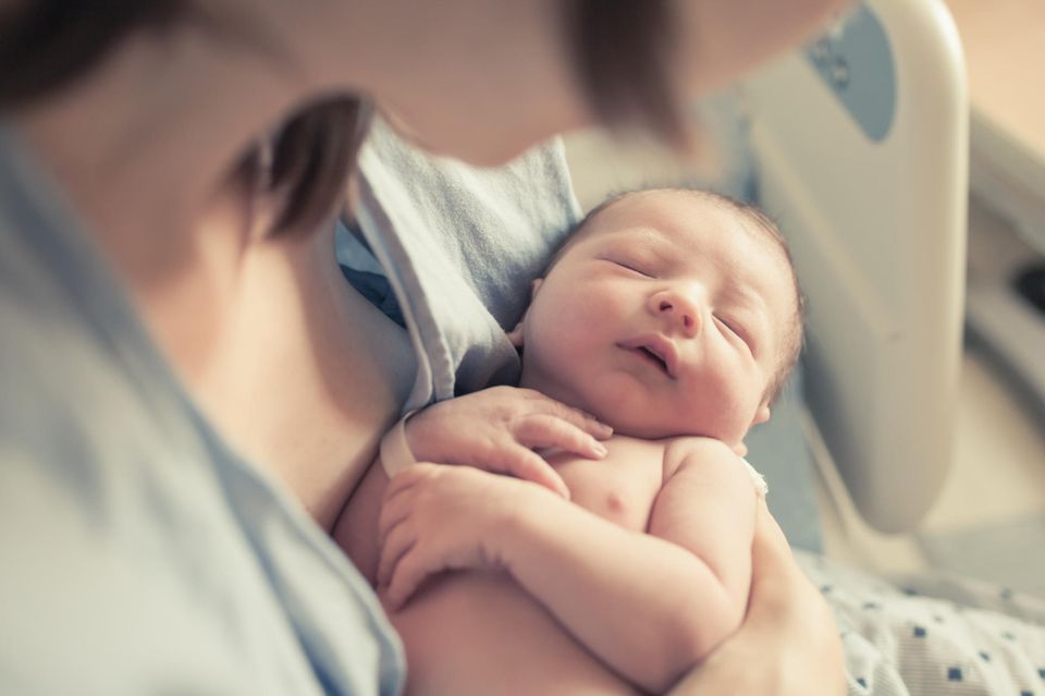Erste Tage mit Baby: eine Mutter hält ihr Neugeborenes im Arm