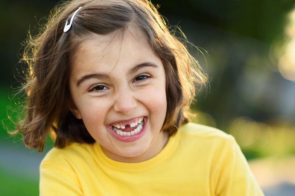 Fröhliches Mädchen mit Zahnlücke und gelbem Pullover