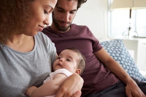 Studie zur Erwartungshaltung: Mutter und Vater sitzen mit einem Baby auf dem Sofa