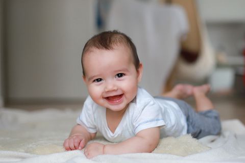 Ein Baby liegt auf dem Bauch und lächelt