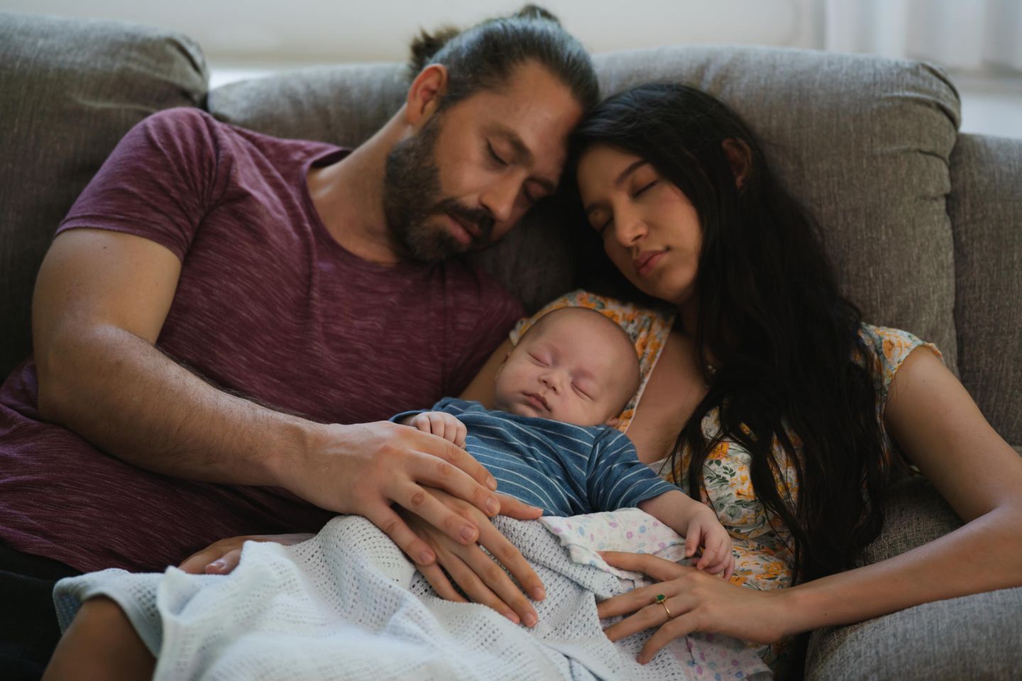 Schlafbegleitung: ein junges Paar schläft mit ihrem Neugeborenen auf dem Sofa